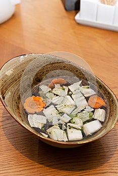 Soup with vegetables and shiitake mushrooms in a bowl, Asian cuisine, vegetarian food. Vertical orientation, hard light