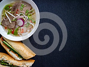 Soup from Vietnam and banh mi heo nuong on a grey background with copy space photo