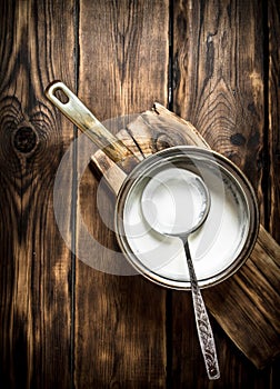 Sour cream in the pan with a ladle.