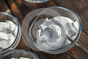 Sour cream sauce in a glass portioned gravy boat on a wooden table. Close-up. Top view