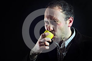 Sour lemon expression sucking man in black