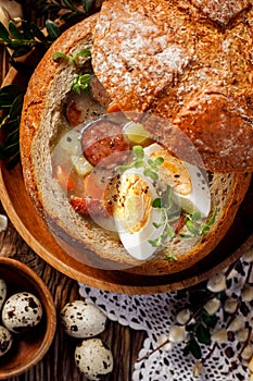 The sour soup Å»urek made of rye flour with smoked sausage and eggs served in bread bowl.