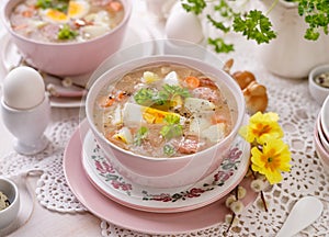 The sour soup ÃÂ»urek, polish Easter soup with the addition of sausage, hard boiled egg and vegetables in a ceramic bowl.