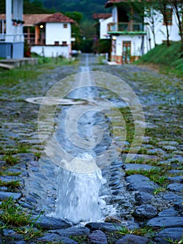 Source of clean water on a stone paved road with blurred town in the background vertical