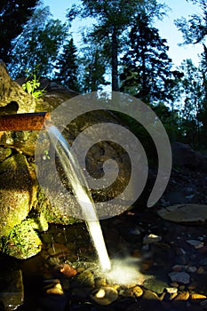 The source of natural water, wellspring, flowing through rocks in forest photo