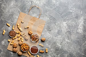 A source of protein for vegetarians: nuts and seeds top view on a concrete background with paper package.