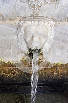 Source of Sariza with mineral water in the form of a lion`s head Andros island, Greece, Cyclades