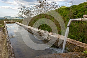Source of spring water in the forest, small mountain village in the background