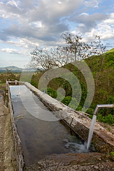 Source of spring water in the forest, small mountain village in the background