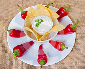 Sourcream with corn chips and red hot chilli peppers.