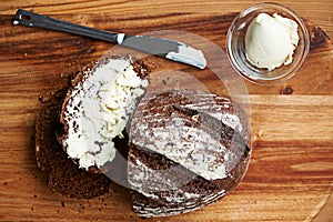 Sourdough, bread and butter on slice for baking, nutrition and carbs on kitchen table or fibre. Top view, wheat and rye