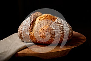 Sourdough bread on linen cloth on brown chopping board.