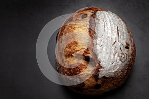 Sourdough bread with mixed fruits and nuts on dark cement background.