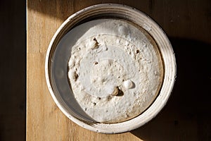 Sourdough bread proofing in a basket with visible gas bubbles. Homemade baking