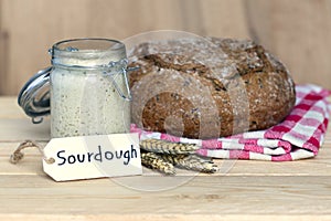 sourdough label with yeast jar, bread, wheat ears on wooden background