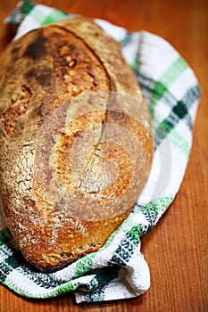 Sourdough loaf bread with a slash and crusty crust on a teatowel photo