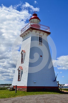 Souris Lighthouse against bright blue sky and white clouds photo