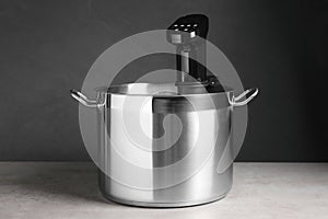 Sous vide cooker in pot on light grey table. Thermal immersion circulator