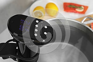 Sous vide cooker in pot on white table, closeup. Thermal immersion circulator