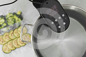Sous vide cooker in pot on white table, closeup. Thermal immersion circulator