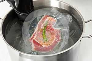 Sous vide cooker and vacuum packed meat in pot on table, closeup. Thermal immersion circulator