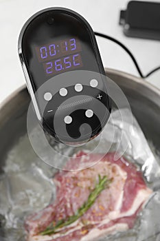 Sous vide cooker and vacuum packed meat in pot on table, closeup. Thermal immersion circulator