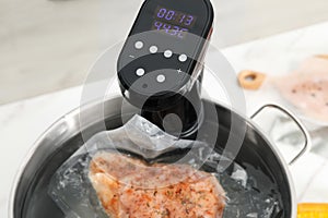 Sous vide cooker and vacuum packed meat in pot on white table, closeup. Thermal immersion circulator