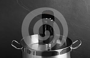 Sous vide cooking. Thermal immersion circulator in pot on dark grey background