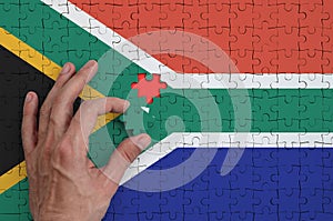 South Africa flag is depicted on a puzzle, which the man`s hand completes to fold