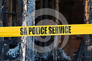 South African police tape in front of a burnt house