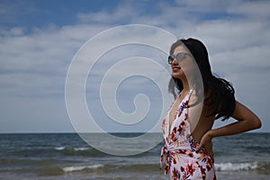 South American woman, young and beautiful, brunette with sunglasses and swimsuit posing happily on the beach. Concept sea, sand,