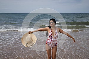 South American woman, young and beautiful, with sunglasses, brunette with swimsuit and hat with the word summer held in her hand