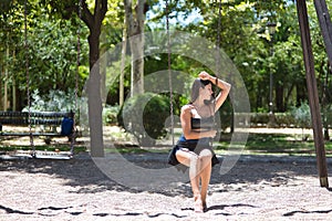 South American woman, young, pretty, brunette with leather top and short jeans, sitting on a swing very sad and alone. Concept