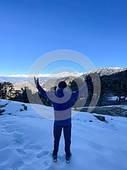 South Asian man atop a snow-covered hill in Chandrashila trek, Uttarakhand