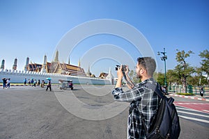 South Asian tourists backpackers taking photo Wat Phra Kaew or Emerald Buddha Temple a tourist landmark in Bangkok Thailand