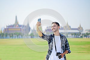 South Asian tourists backpackers taking selfie with smartphone while traveling on holidays in Wat Phra Kaew or Emerald Buddha