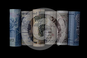 South-East Asian money notes rolled against a black background