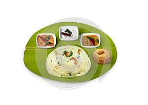 South Indian breakfast pongal, ven pongal ,with coconut chutney, red chutney, and sambar served on banana leaf photo