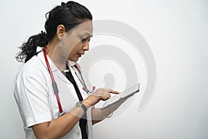A south Indian female doctor in 30s holding tablet in white coat and red stethoscope in white background