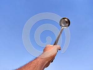 South Indian man hand holding silver laddle .