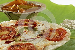 South Indian snack food onion and tomato uttapam with sambar and chutney.