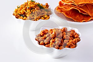 South indian spicy crunchy mix Nimco or Namkeen with peanut, rice, curry leaves and spice white bowl background isolated