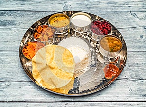 south indian vegetarian meal thali vegetables, curry, rice, raita, korma, kesari halwa and chapati served in dish isolated on