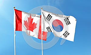 South Korea flag and Canada flag. waving in the blue sky