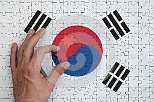 South Korea flag is depicted on a puzzle, which the man`s hand completes to fold