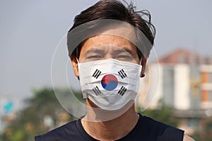 South Korea flag on hygienic mask. Masked Asian man prevent germs. concept of Tiny Particle protection or virus