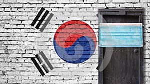 South Korea flag painted on brick wall and closed door with medical mask protected