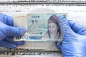 South Korea money, Won, banknote kept in rubber gloves. The concept of economy and financial threats during the Coronavirus pandem photo