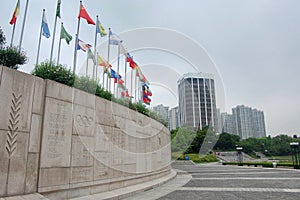 South Korea Olympic Park summer games with global flags flying on a cloudy day with the Olympic Plaque on the concrete ti