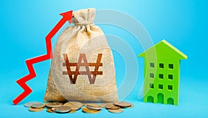 South korean won money bag with red up arrow and residential building. Return on investment. Increase in prices for apartments